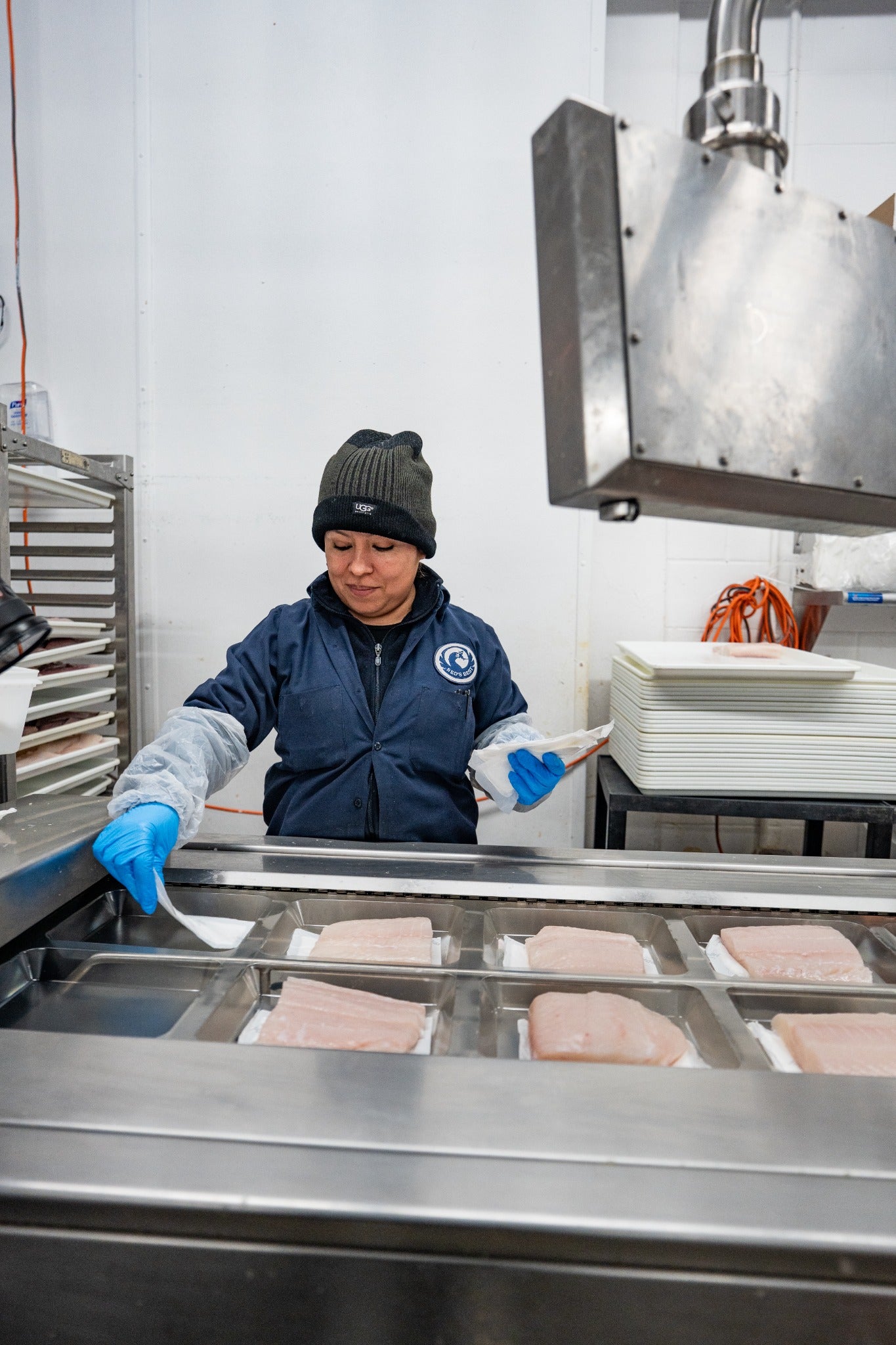 A woman placing halibut portions into packaging machinery
