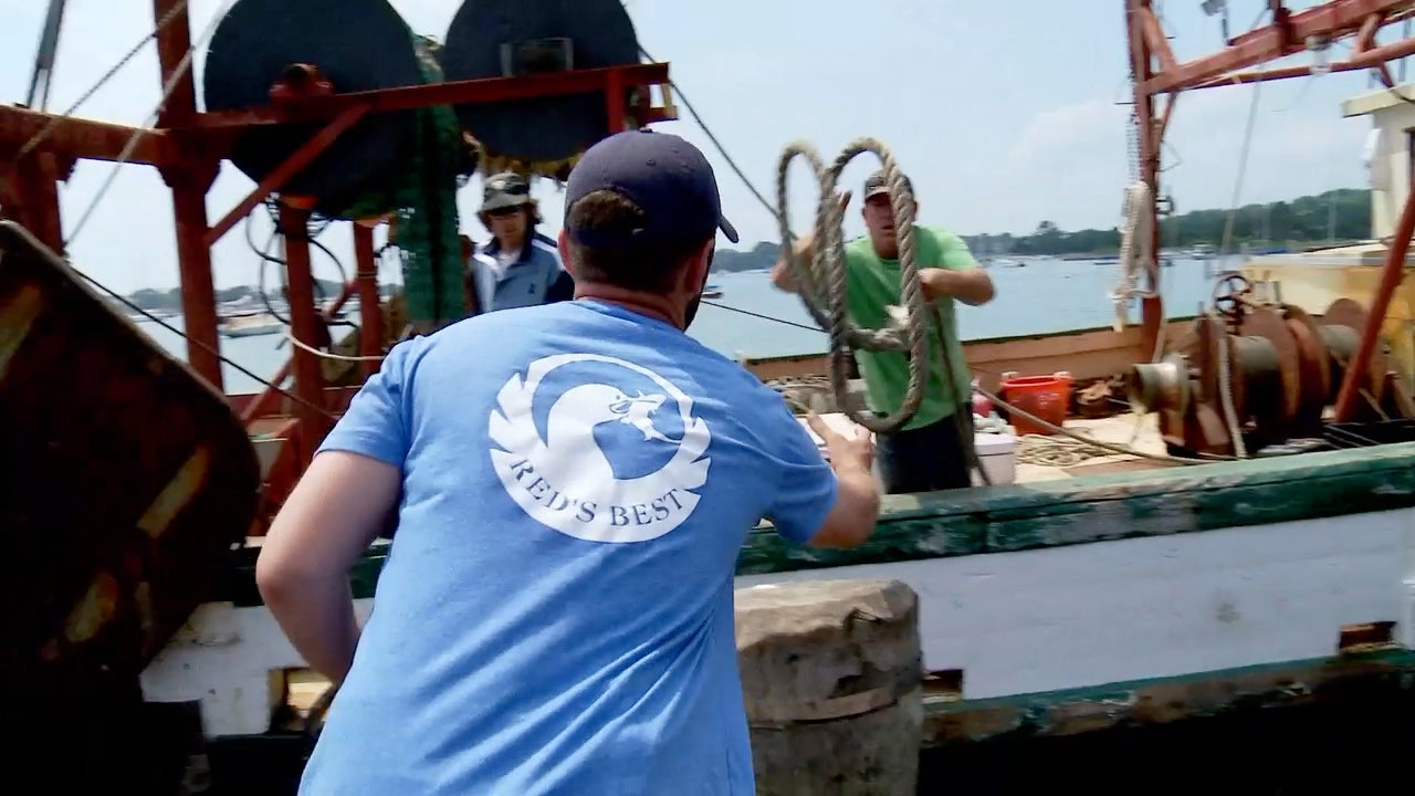 A Red’s Best crew member receiving a rope thrown from a fishing boat