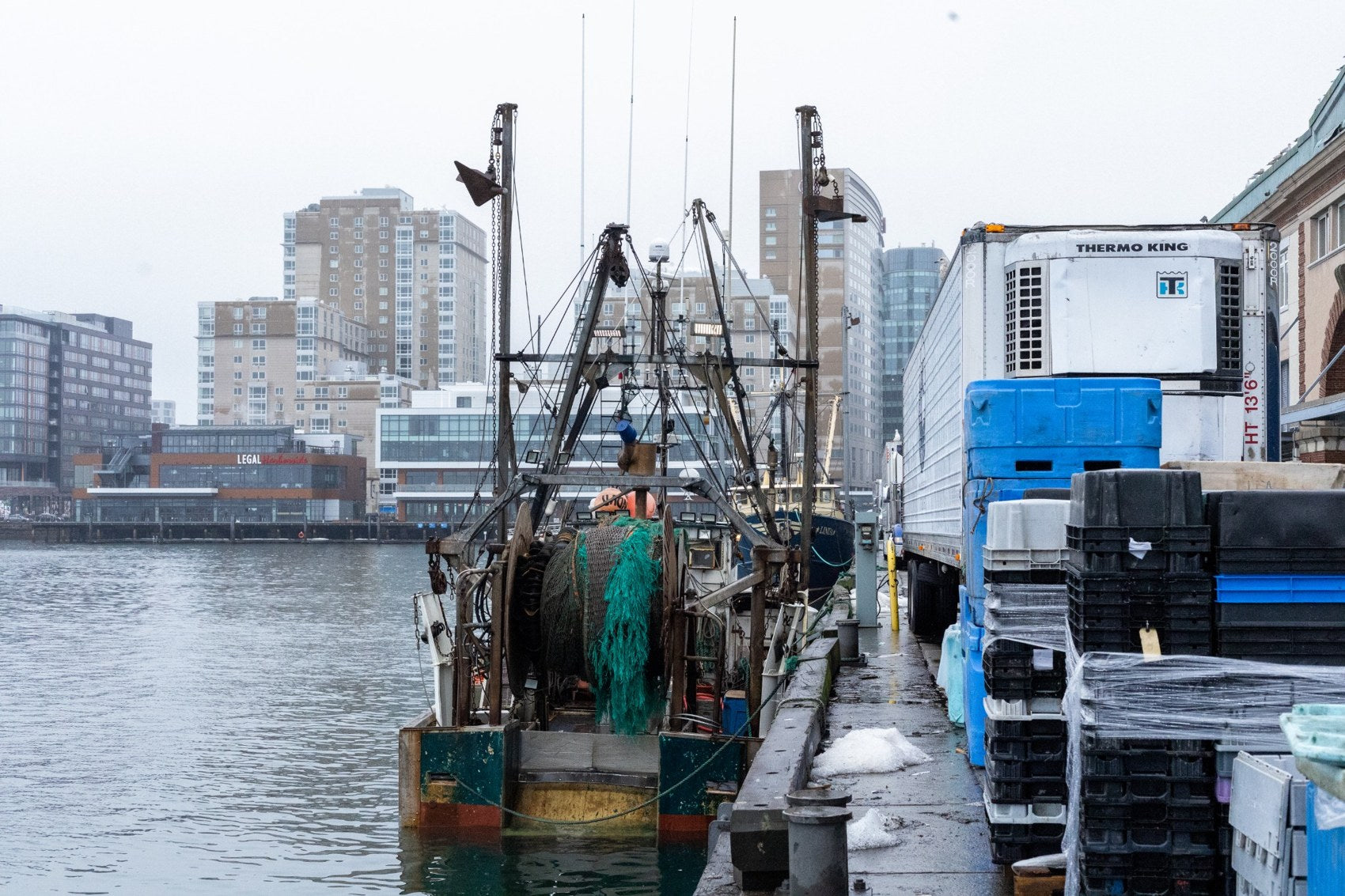 Fishing boat alongside seafood containers and a refrigerated truck at the Boston Fish Pier